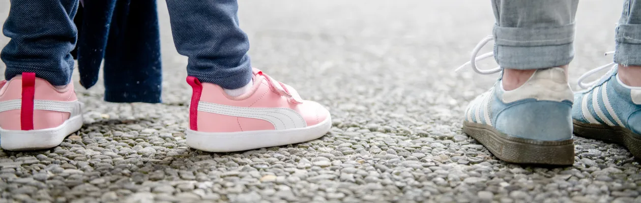 Das Foto zeigt zwei paar Schuhe von zwei Personen, die nebeneinander auf dem Forum der RUb stehen: Eine Erwachsene  mit blauen Sneakern und ein Kind mit pinken Sneakern und Klettverschlüssen